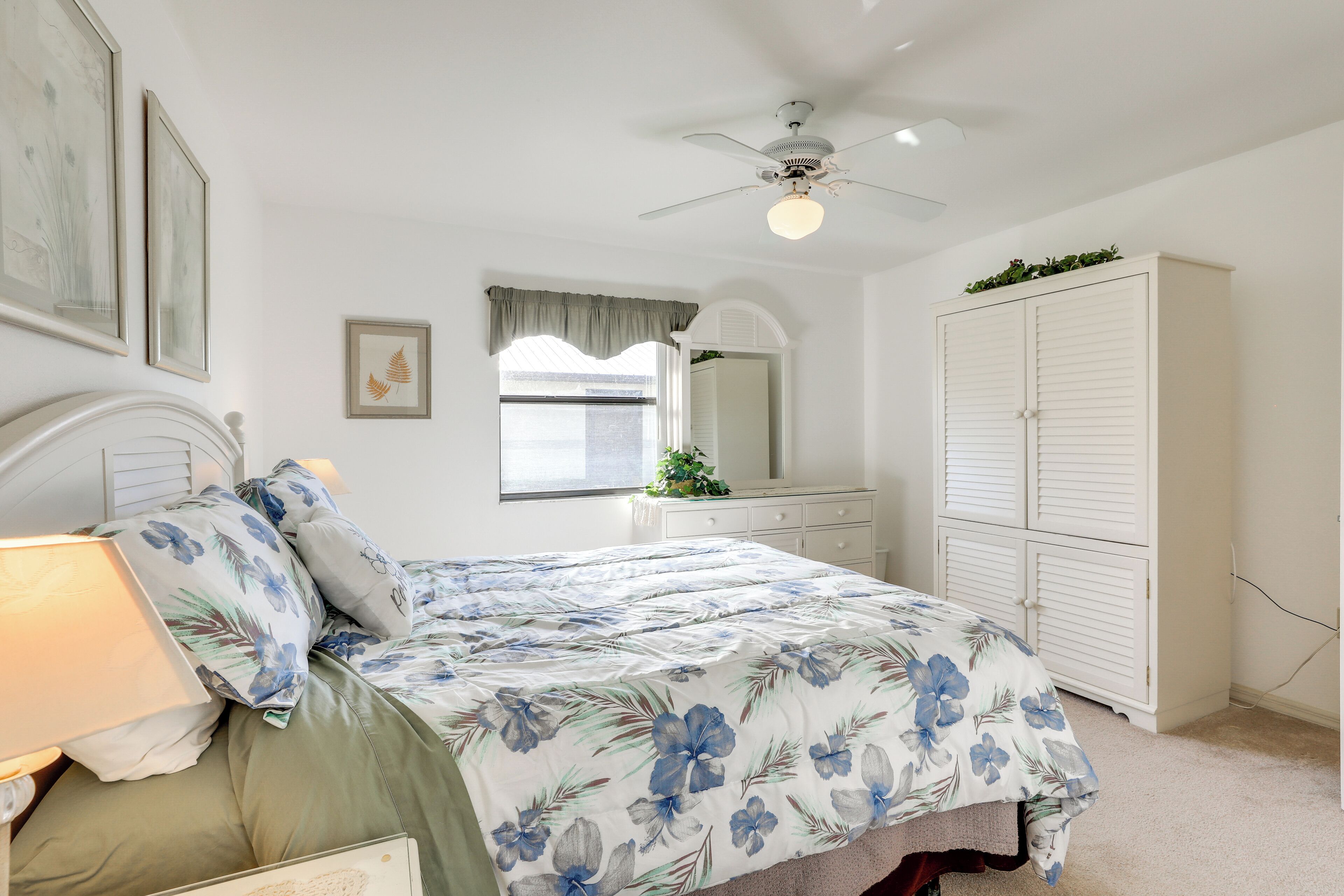 A bedroom with a bed, a nightstand, a dresser, a wardrobe, and a ceiling fan.