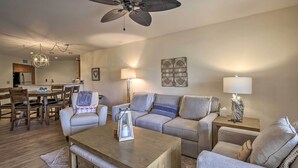 A modern living room with a dining area, a ceiling fan, and a kitchen in the background. - St Pete Condo w/ Heated Pool - 3 Miles to Beach! (St. Petersburg)
