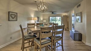 A dining area with a chandelier, wooden chairs, a table, and a ceiling fan. - St Pete Condo w/ Heated Pool - 3 Miles to Beach! (St. Petersburg)