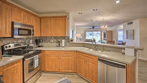 A modern kitchen with wooden cabinets, stainless steel appliances, and a large island with a sink. - St Pete Condo w/ Heated Pool - 3 Miles to Beach! (St. Petersburg)