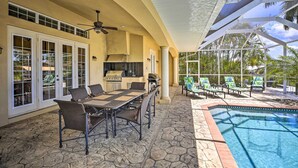 A covered outdoor area with a pool, dining table, chairs, and a grill. - 3 Mi to Downtown Cape Coral: Canal-front Villa (Cape Coral)