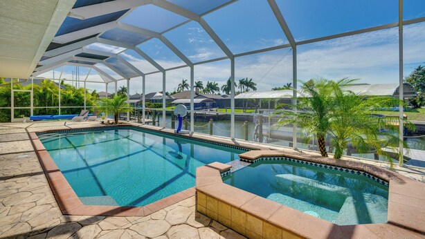 An indoor swimming pool with a glass ceiling, surrounded by palm trees and lounge chairs. - 3 Mi to Downtown Cape Coral: Canal-front Villa (Cape Coral)