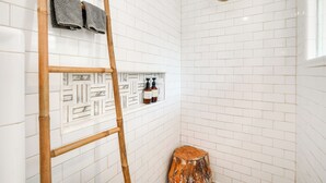 A bathroom with white subway tiles, a wooden ladder, a wooden stool, and a showerhead. - Chic Getaway in Desirable South Tampa District! (Tampa)