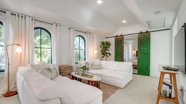 A spacious living room with a white sectional sofa, a round coffee table, and a large window with curtains. - Chic Getaway in Desirable South Tampa District! (Tampa)