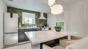 A modern kitchen with a large island, dark cabinets, and a green-tiled backsplash. - Chic Getaway in Desirable South Tampa District! (Tampa)