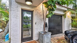 A house with a textured exterior, a black door, and a garage door. - Chic Getaway in Desirable South Tampa District! (Tampa)