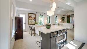 A modern kitchen with a central island, recessed lighting, and a dining area with a white sofa and chairs. - Chic Getaway in Desirable South Tampa District! (Tampa)