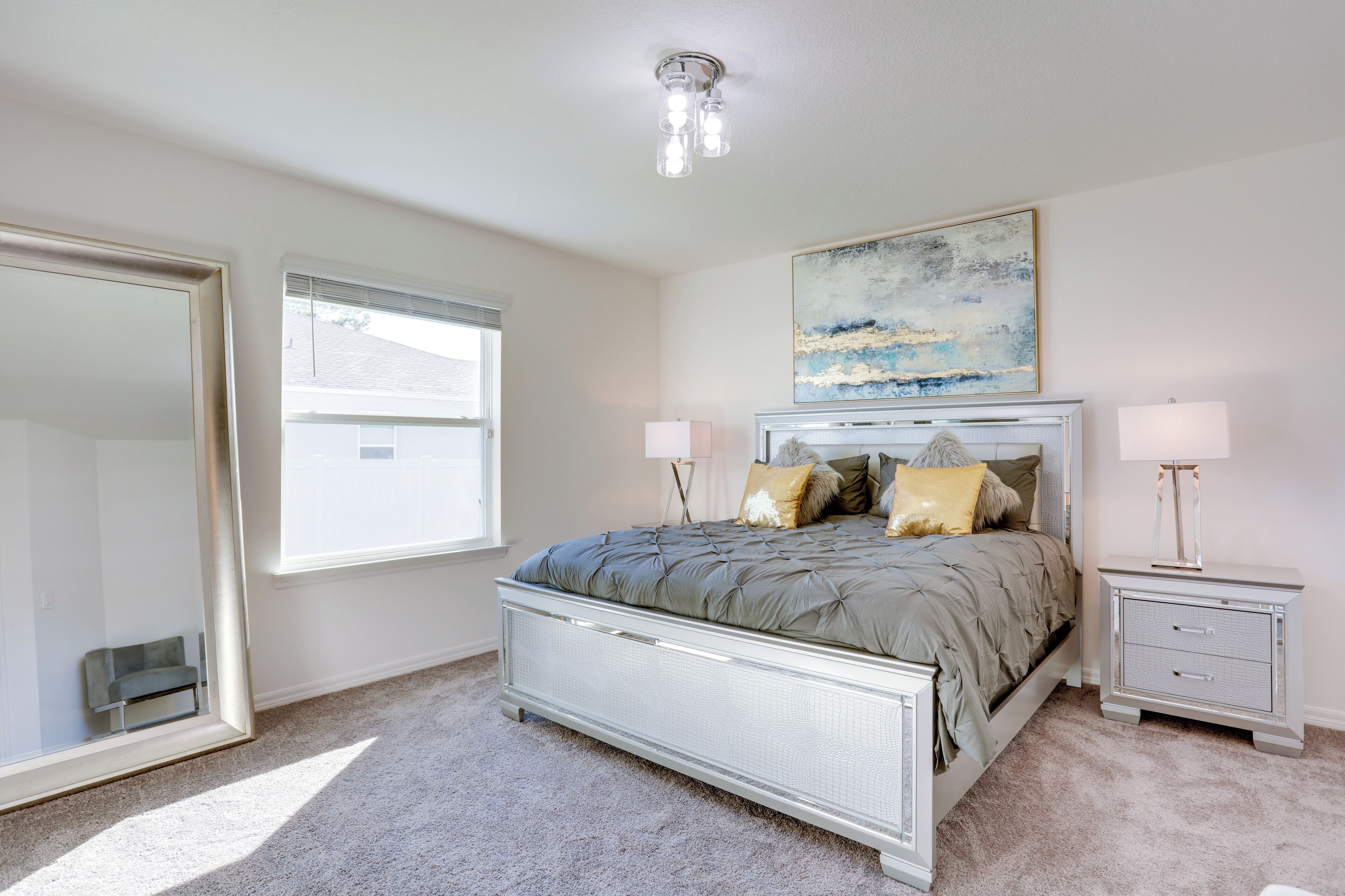 A bedroom with a large bed, bedside tables, a mirror, and a painting on the wall.