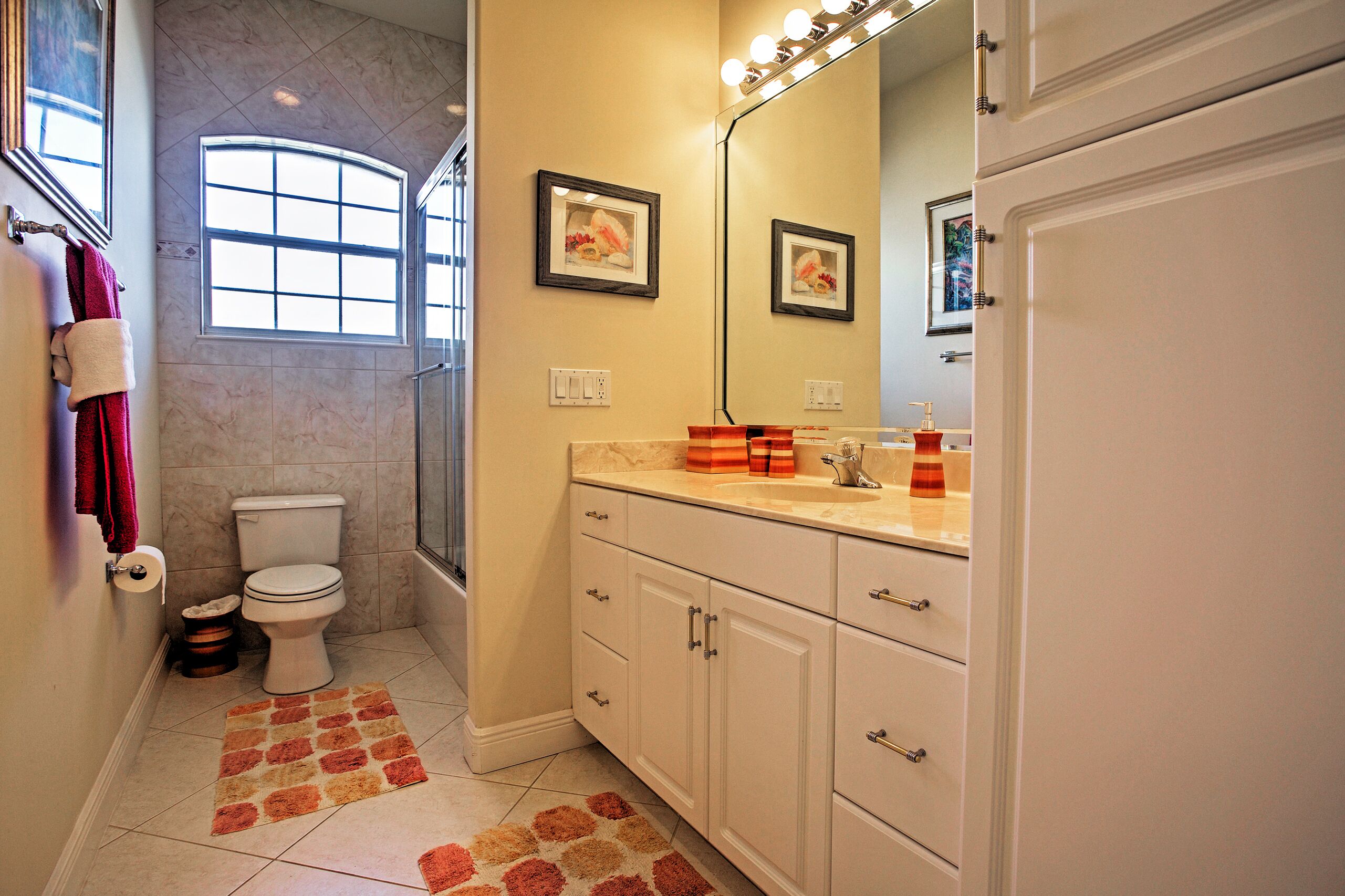 A bathroom with a toilet, sink, vanity, and a large mirror.