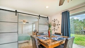 A dining area with a wooden table, leather chairs, and a view of the outdoors through a large window.