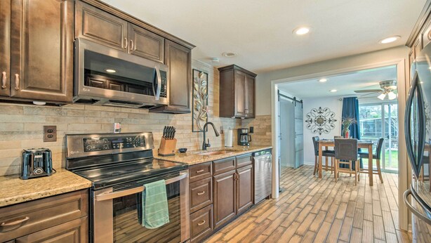 A kitchen with stainless steel appliances, wooden cabinets, and a herringbone floor pattern.