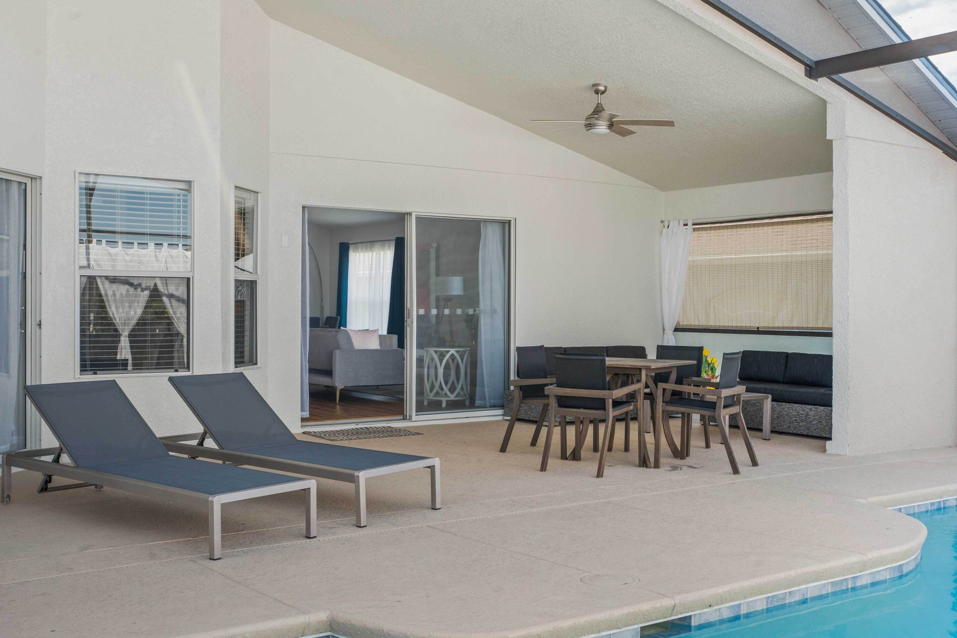 Un espace aménagé au bord de la piscine, avec des chaises longues, une table et un canapé.