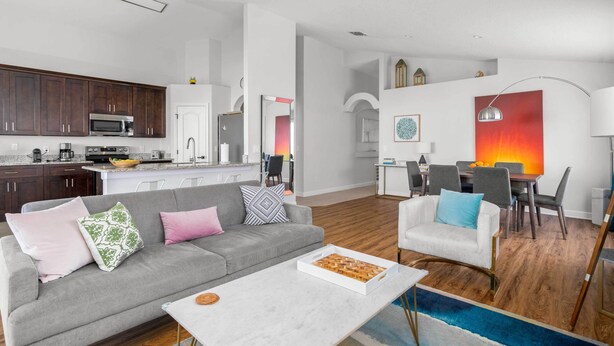 A modern living room with a grey sofa, a coffee table, and a dining area with a table and chairs. - Davenport Vacation Home w/ Pool, Spa & Game Room! (Davenport)