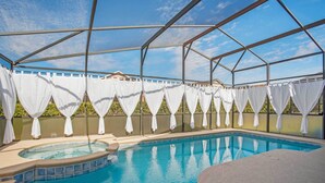 A covered swimming pool with a hot tub, surrounded by white curtains and a clear blue sky. - Davenport Vacation Home w/ Pool, Spa & Game Room! (Davenport)