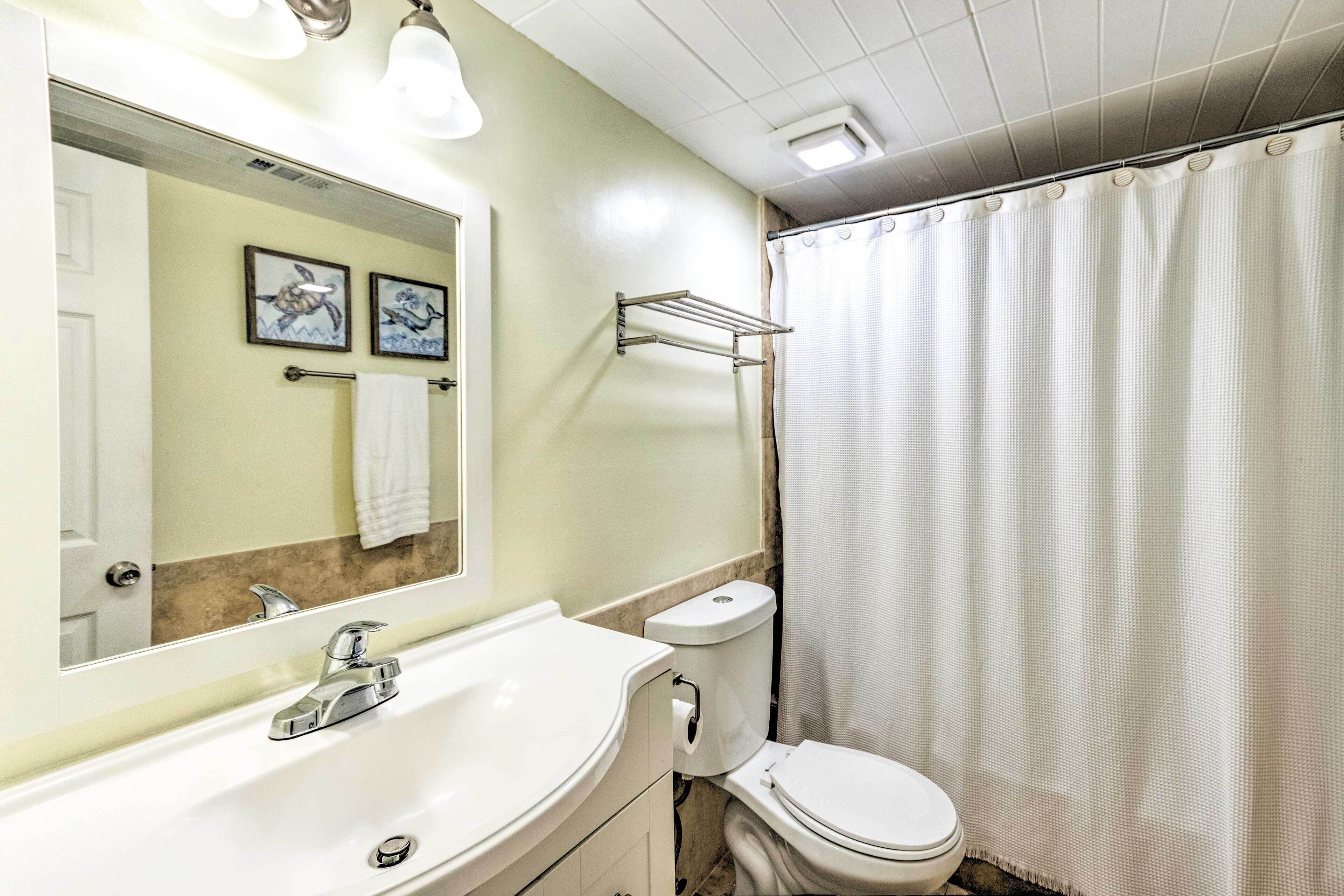 A bathroom with a white sink, a toilet, a towel rack, and a shower curtain.