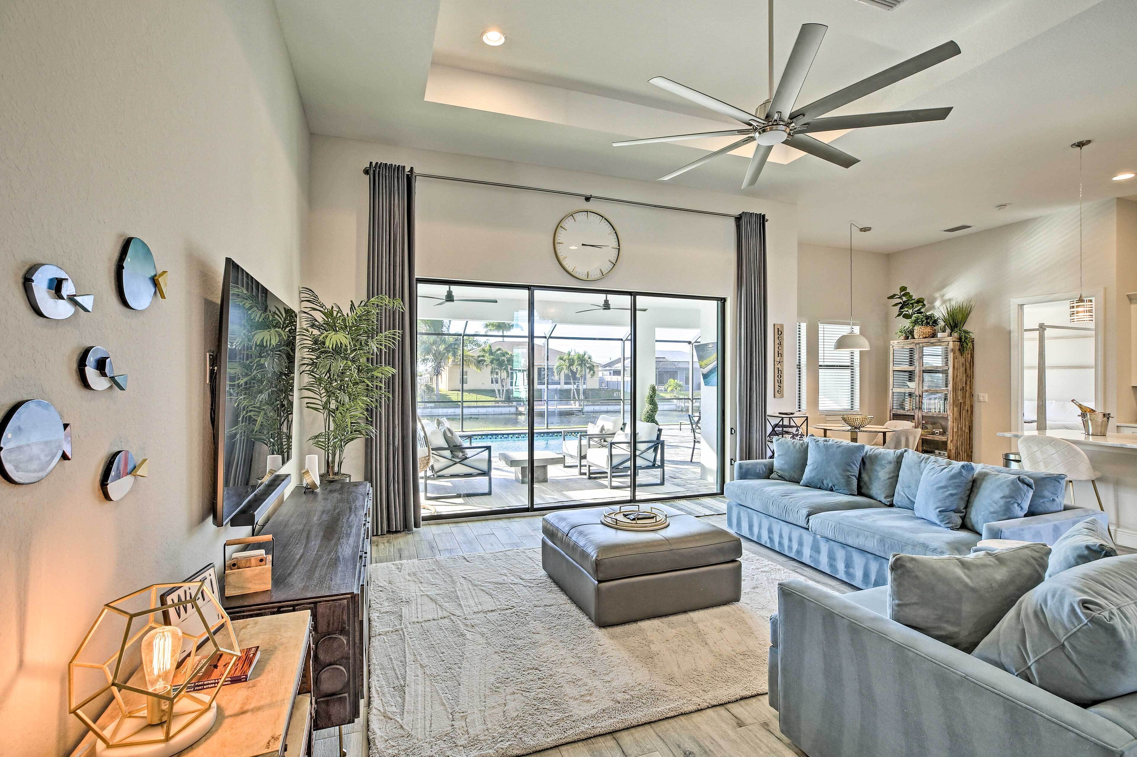 A spacious living room with a large sofa, a coffee table, and a dining area with a view of a pool.
