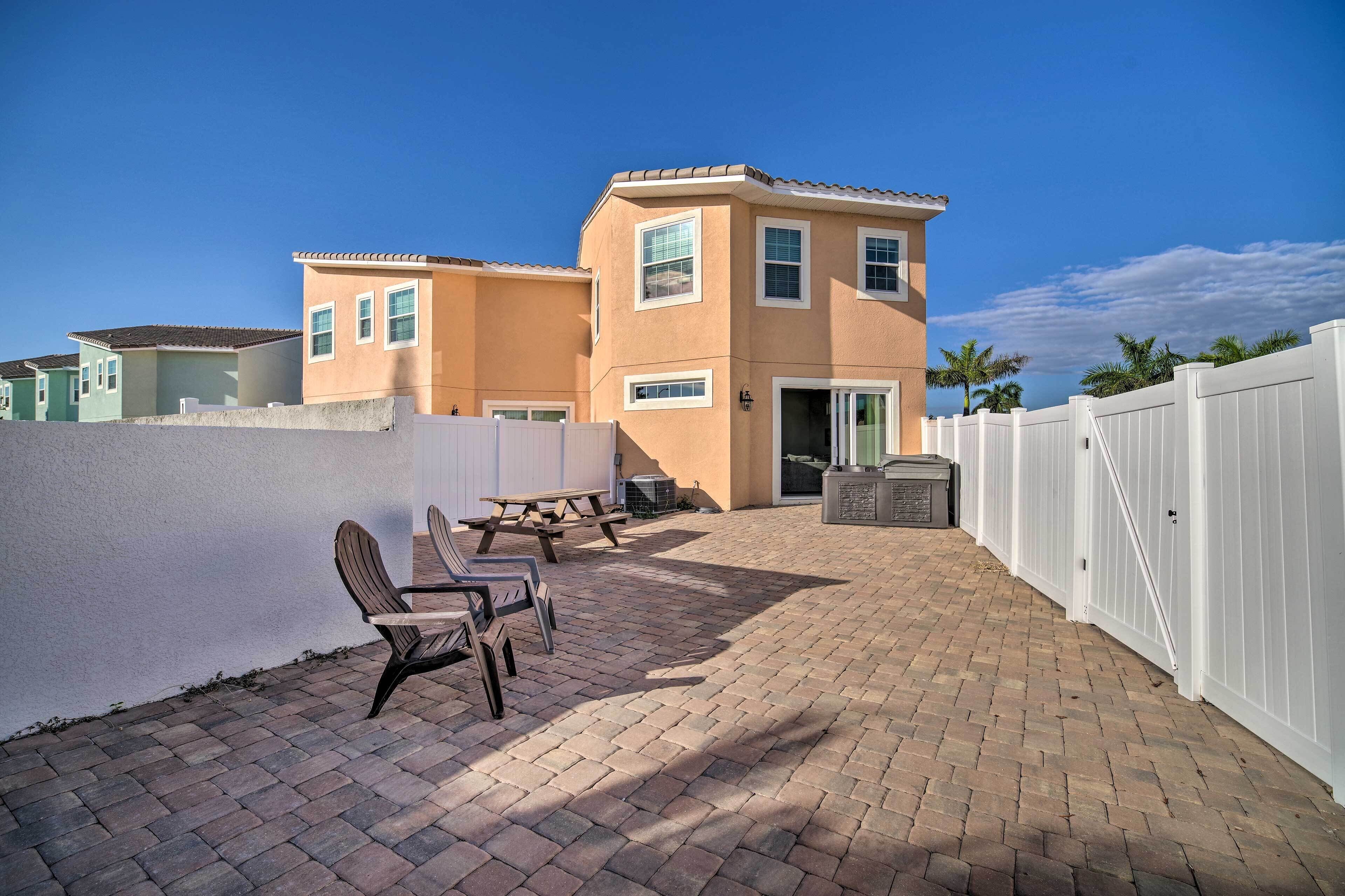 A patio area with brick flooring, a picnic table, and outdoor seating.