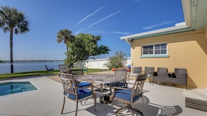 An outdoor patio with a pool, lounge chairs, and a view of the water. - Waterfront Oasis! Heated Pool, 2 Docks & Boat Lift (Palmetto)