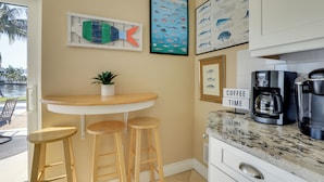 A kitchen with a bar area, stools, a coffee machine, and framed fish illustrations on the wall. - Waterfront Oasis! Heated Pool, 2 Docks & Boat Lift (Palmetto)