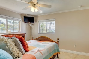 A bedroom with a bed, a ceiling fan, a TV mounted on the wall, and windows with views of greenery. - Waterfront Oasis! Heated Pool, 2 Docks & Boat Lift (Palmetto)