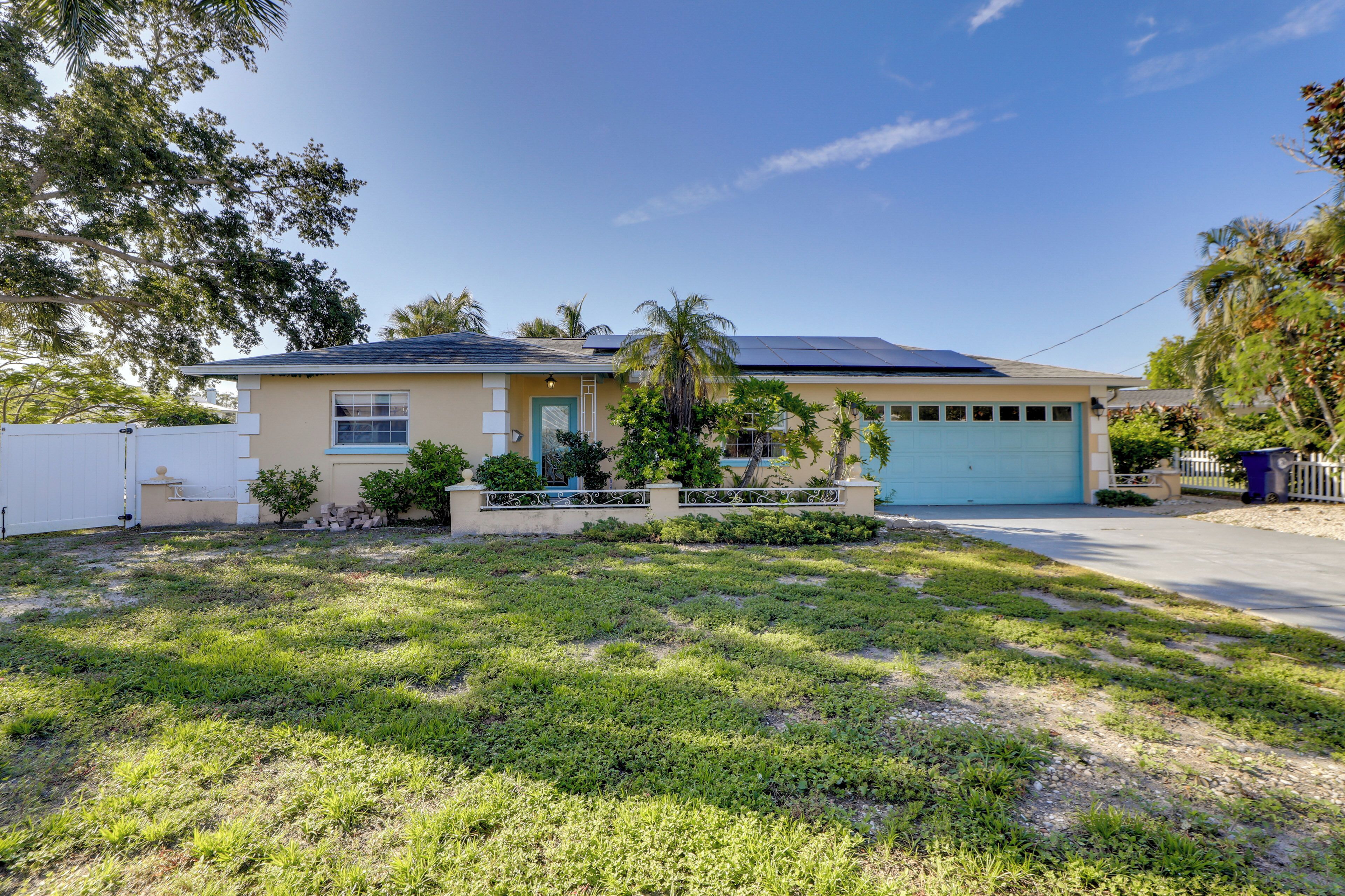 A residential house with a garage, solar panels, and a well-maintained lawn.