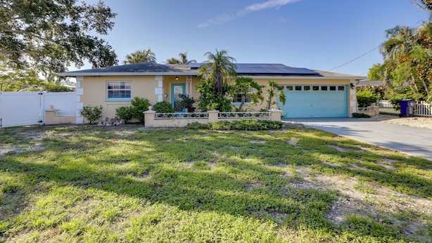 A residential house with a garage, solar panels, and a well-maintained lawn. - Waterfront Oasis! Heated Pool, 2 Docks & Boat Lift (Palmetto)