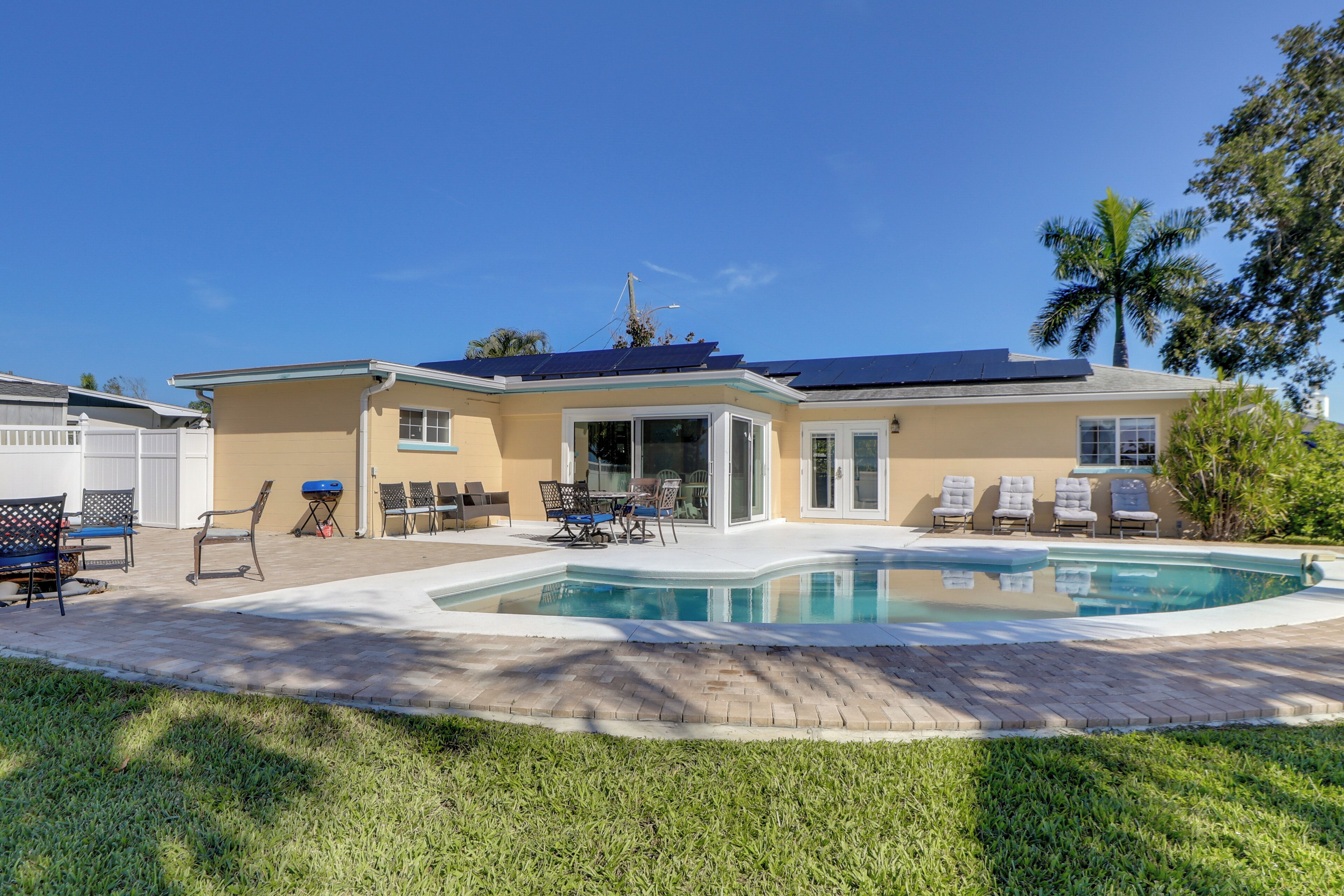 A residential property with a swimming pool, outdoor seating, and a covered patio area.