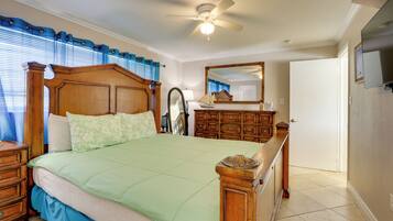 Un dormitorio con una cama de madera, una mesita de noche, un aparador, un espejo y un ventilador de techo.