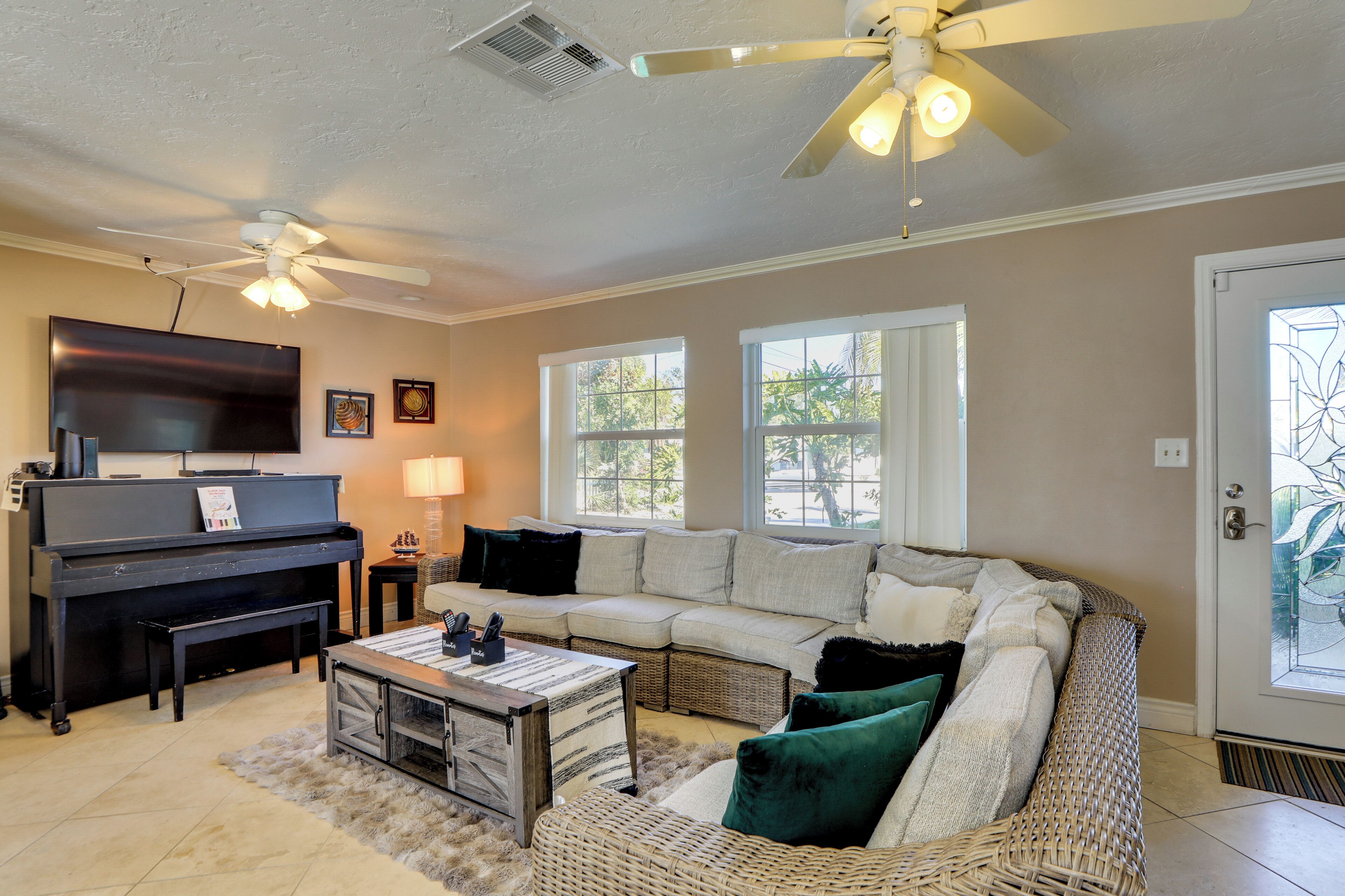 A living room with a piano, a sofa, a coffee table, and a ceiling fan.