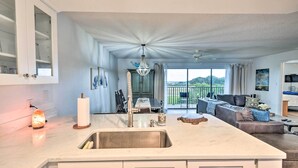 Eine moderne Küche mit einer großen Kochinsel, ein Essbereich mit Blick und ein Wohnzimmer mit Sofa und Fernseher.
