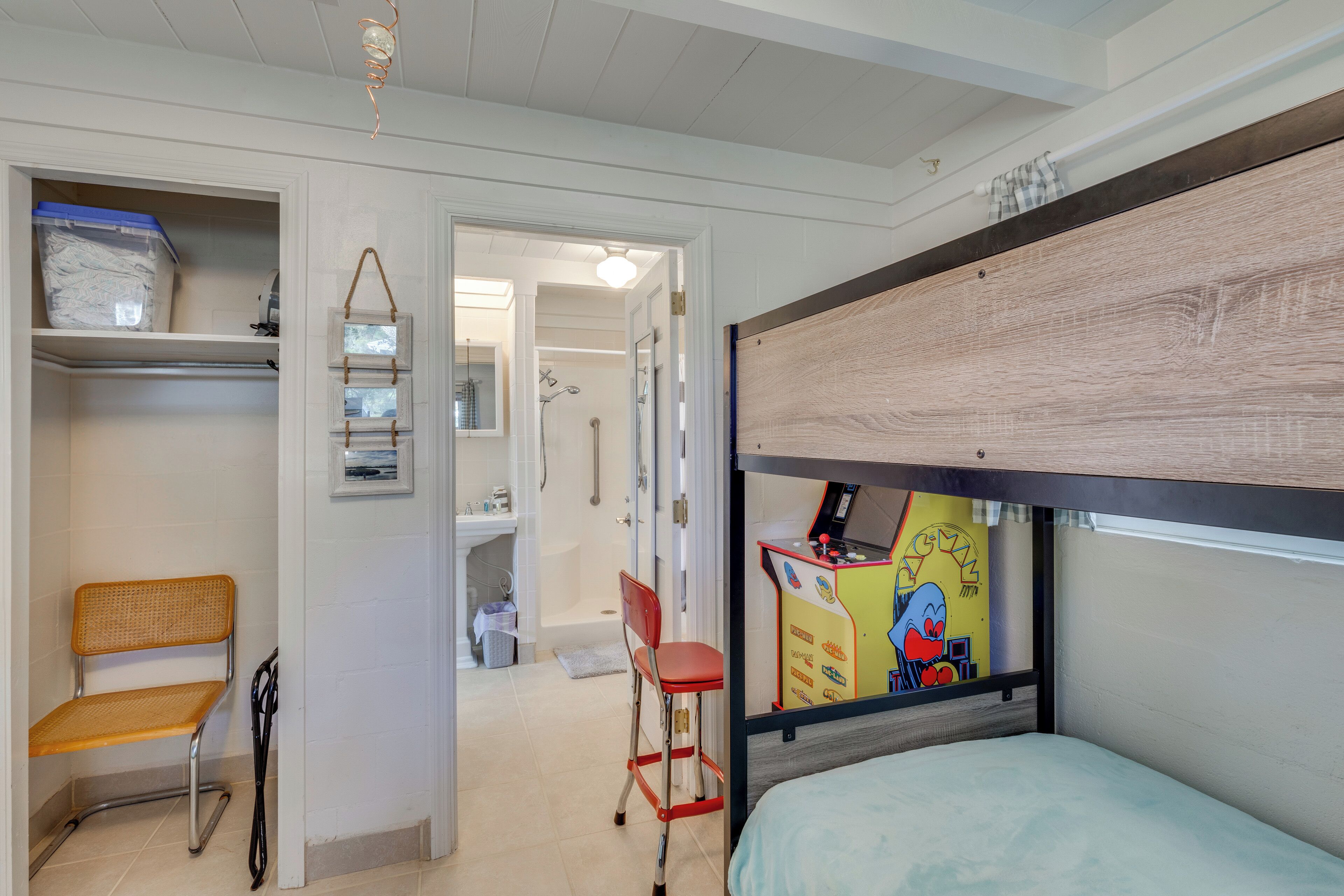 A bedroom with a bunk bed, a chair, a desk, and a bathroom visible through an open door.