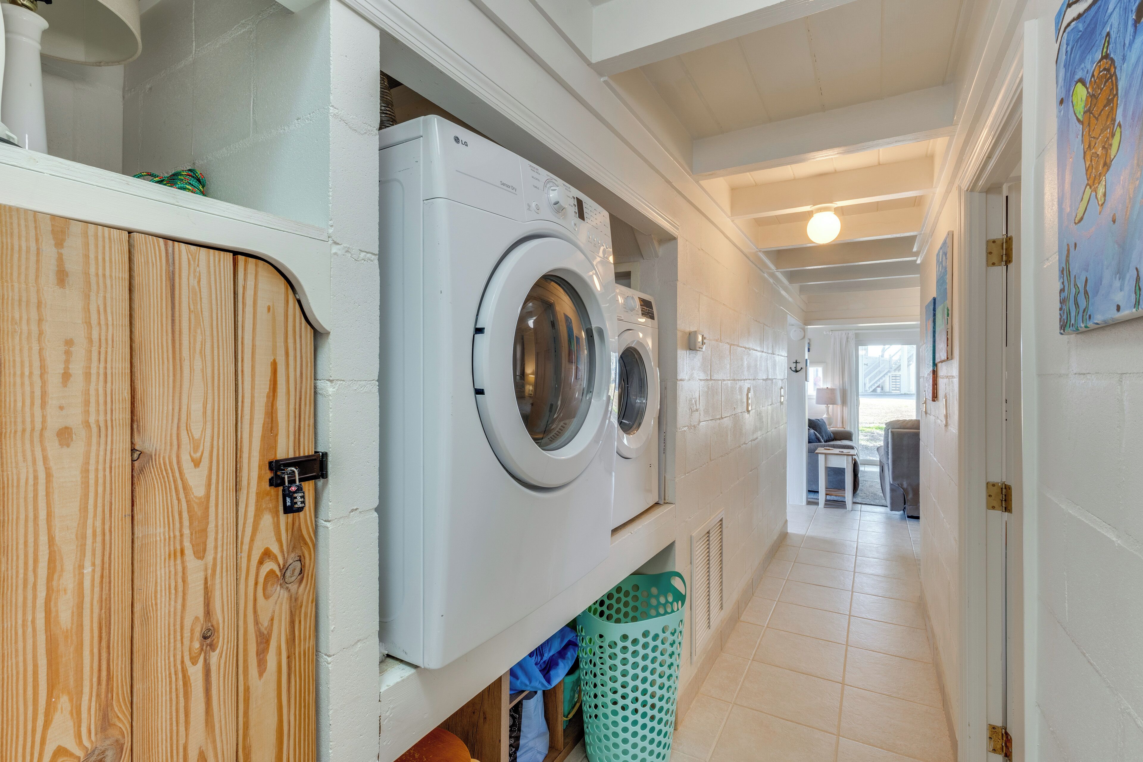 Een wasserette met twee voorladers, een houten kast en een groene wasmand.