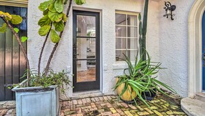 A white stucco building with a tiled patio, a black door, and a window. - South Tampa Studio in Desirable Historic District! (Tampa)