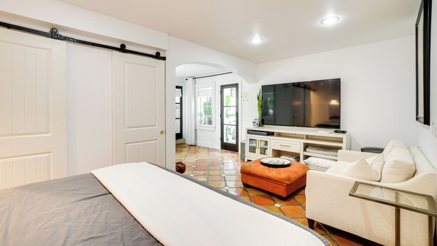 A bedroom with a bed, a TV, a sofa, and a sliding door. - South Tampa Studio in Desirable Historic District! (Tampa)