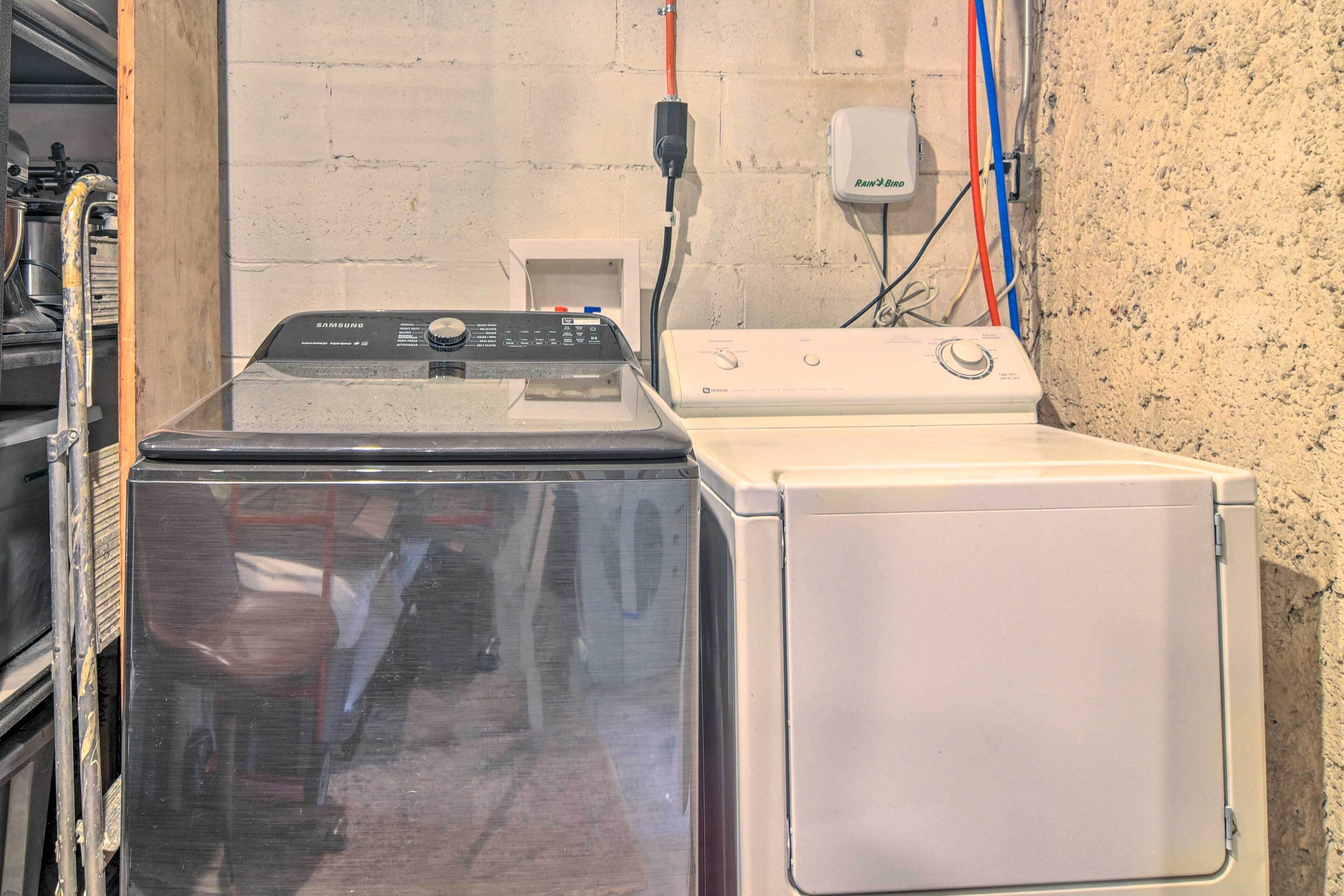 A laundry area with a Samsung washer and dryer, a white wall, and visible plumbing.