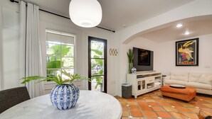 A living room with a round table, a sofa, a TV, and a tiled floor. - South Tampa Studio in Desirable Historic District! (Tampa)
