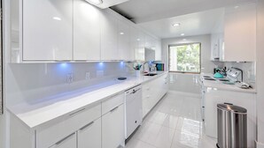 A modern kitchen with white cabinetry, a dishwasher, and a stainless steel trash can. - Waterfront Marco Island House With Shared Dock! (Marco Island)
