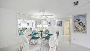 A dining area with a glass table, white chairs, and a ceiling fan. - Waterfront Marco Island House With Shared Dock! (Marco Island)