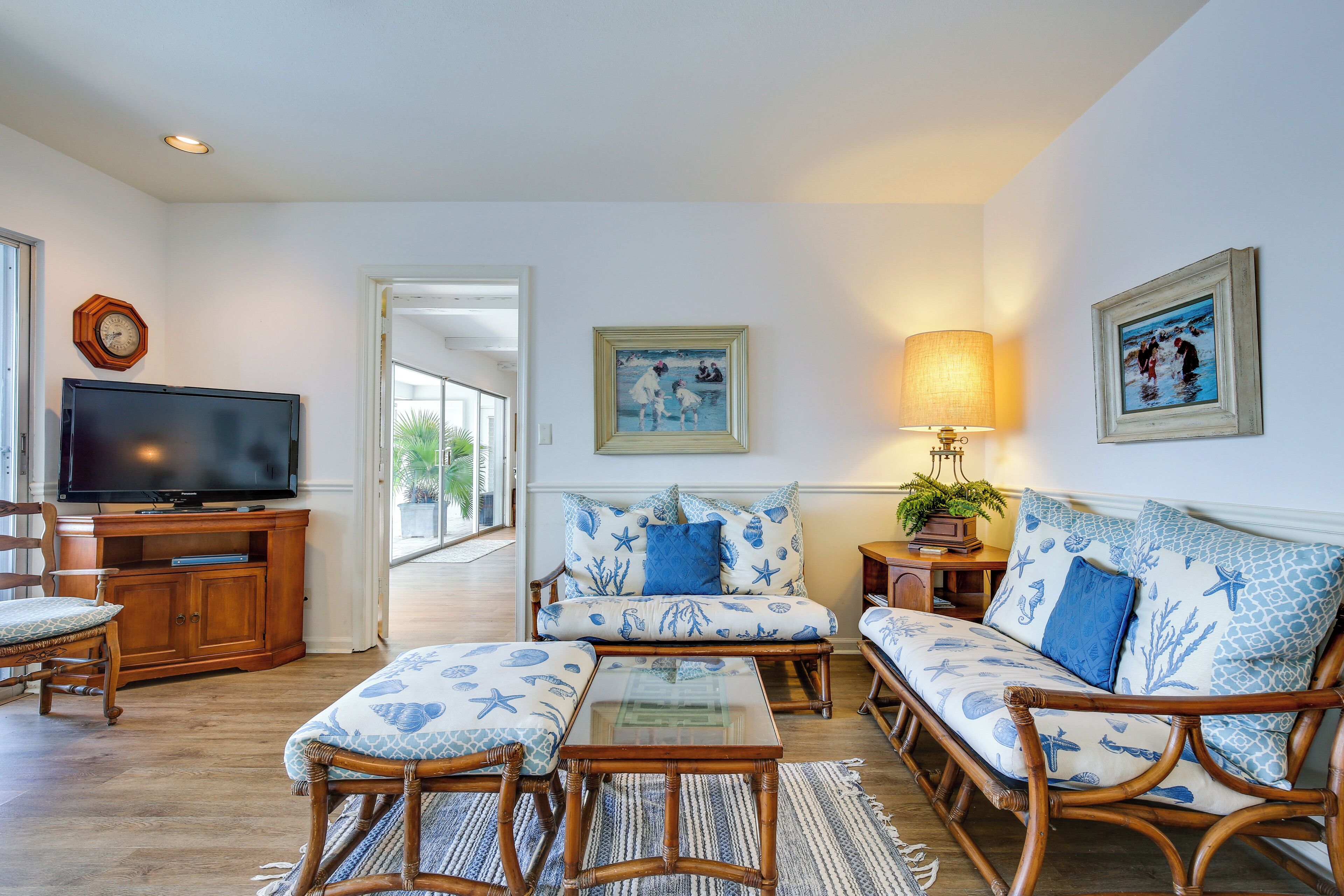 A living room with a television, wicker furniture, and nautical-themed decor.