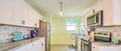 A kitchen with white cabinets, a refrigerator, a microwave, and a stove.