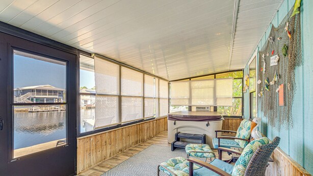 Un espace extérieur abrité, doté de places assises, offrant une vue sur un quai et l’eau, avec des murs en bois et une cheminée.