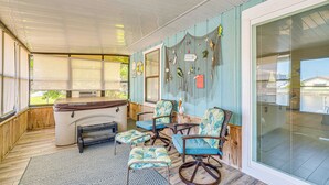 Une véranda abritée avec un coin salon, une petite table et un barbecue.