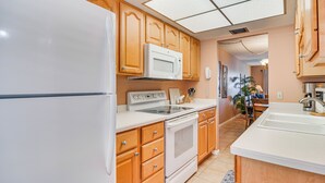 Una cocina con armarios de madera, un refrigerador blanco, un microondas, un horno y un lavamanos.
