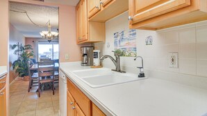 Una cocina con armarios de madera, una encimera blanca y un lavabo.