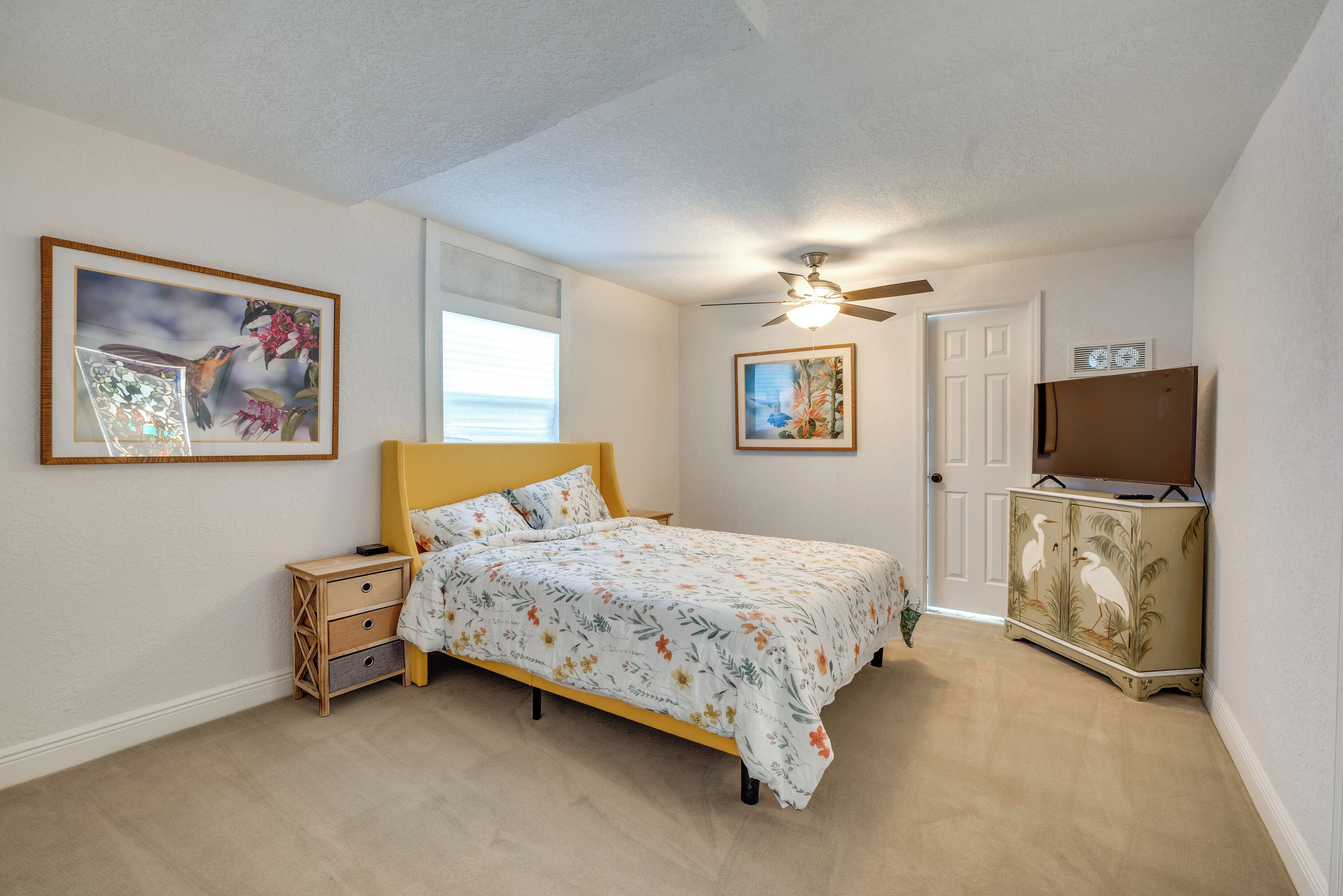 A bedroom with a bed, nightstands, a dresser, and two framed pictures on the walls.