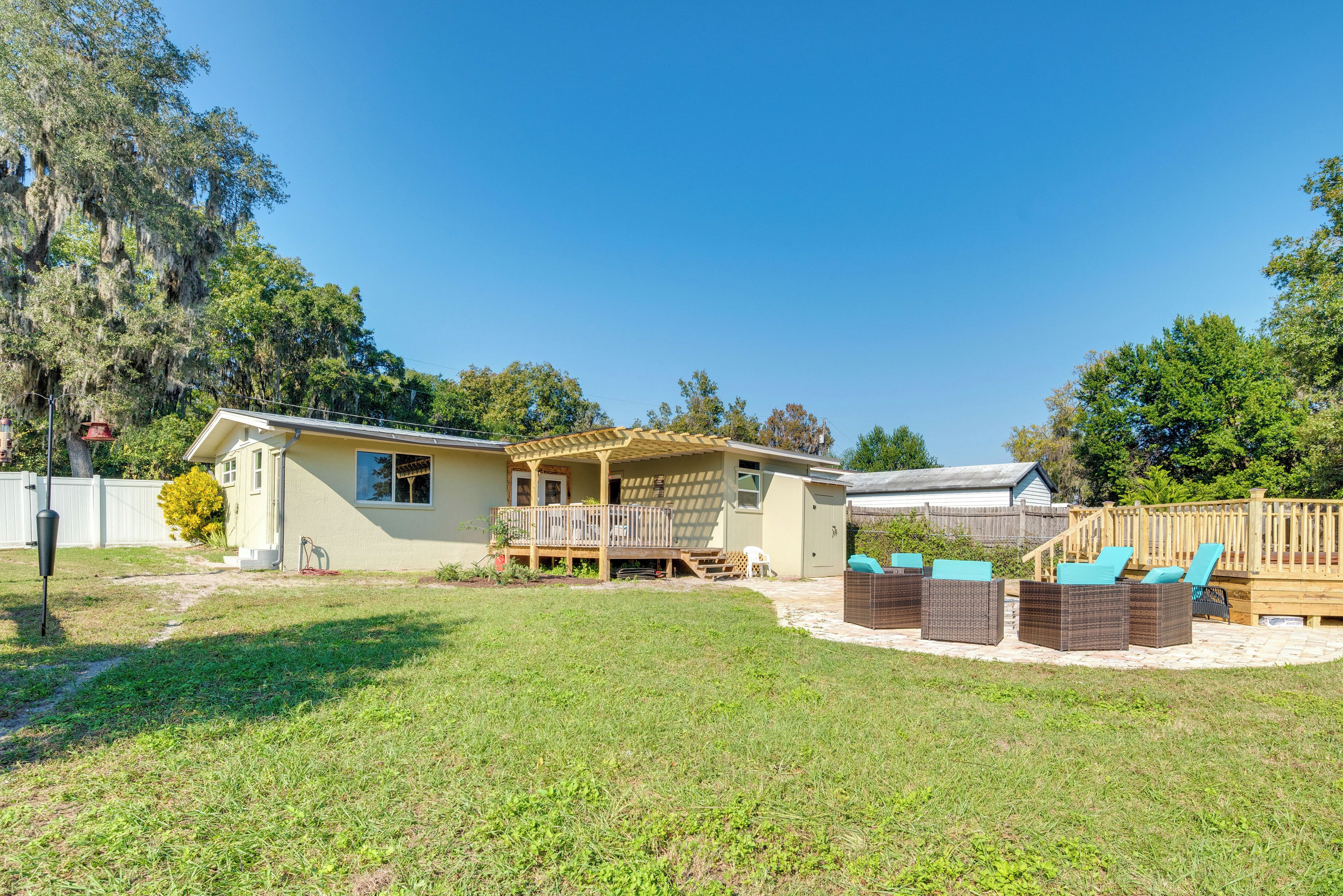 A single-story house with a covered patio area, outdoor seating, and a fenced yard.