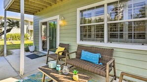 A covered patio with wicker furniture, a wooden table, and a potted plant. - 'tipsy Turtle' Condo w/ Patio & Harbor Access (Destin)