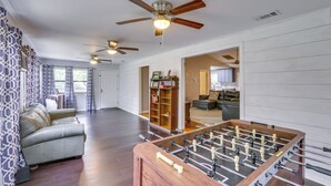 A spacious living room with a foosball table, a sofa, and a ceiling fan. - Waterfront Sopchoppy Hideaway w/ 2 Kayaks! (Sopchoppy)