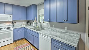 A kitchen with blue cabinets, a white microwave, a stove, a dishwasher, and a marble countertop. - Waterfront Sopchoppy Hideaway w/ 2 Kayaks! (Sopchoppy)