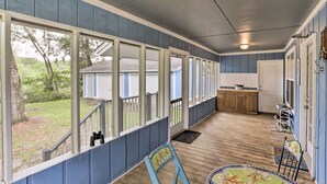 A covered porch with large windows, wooden flooring, and a view of the backyard. - Waterfront Sopchoppy Hideaway w/ 2 Kayaks! (Sopchoppy)